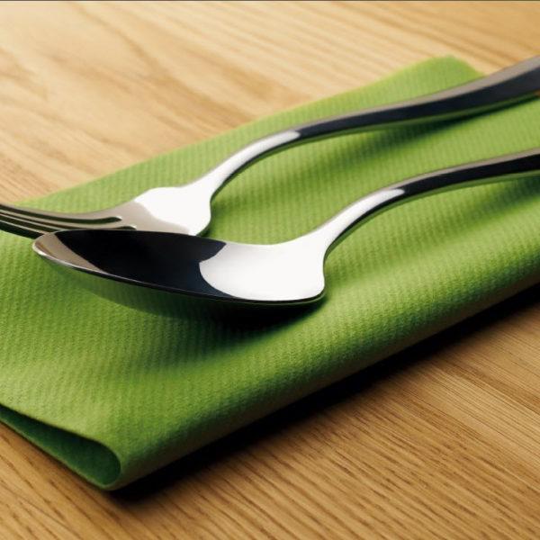 银勺和银叉放在木块上的绿毛巾上
